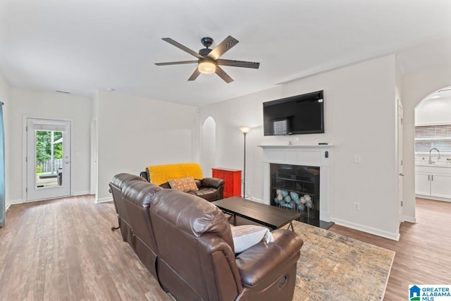5633 Park Side Rd, Hoover, AL 35244 - living room featuring arched walkways, ceiling fan, a fireplace with raised hearth, and light wood-style floors