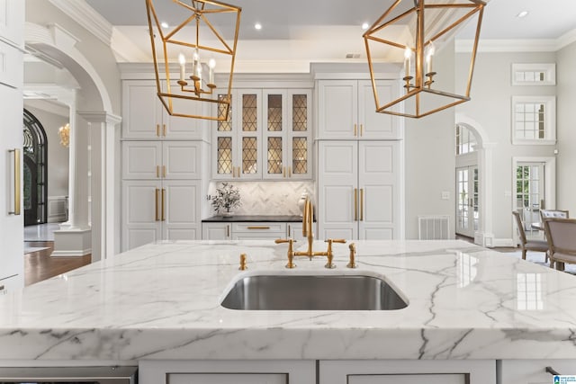 5615 Canongate Ln, Hoover, AL 35242 - kitchen featuring arched walkways, a chandelier, ornamental molding, ornate columns, and backsplash