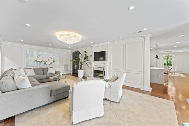 5615 Canongate Ln, Hoover, AL 35242 - living room featuring a decorative wall, crown molding, ornate columns, a glass covered fireplace, and recessed lighting