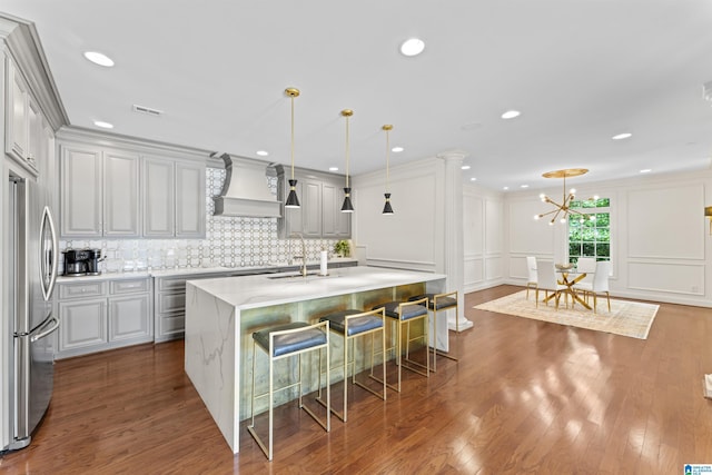 5615 Canongate Ln, Hoover, AL 35242 - kitchen with freestanding refrigerator, premium range hood, an island with sink, a chandelier, and tasteful backsplash