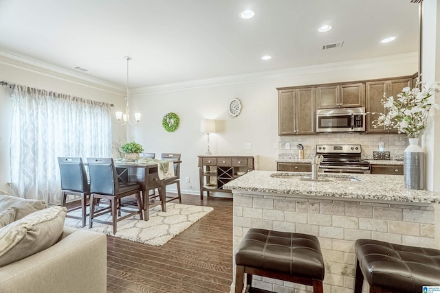 4955 Stonecreek Way, Calera, AL 35040 - kitchen featuring appliances with stainless steel finishes, light stone counters, ornamental molding, dark wood-style flooring, and open floor plan