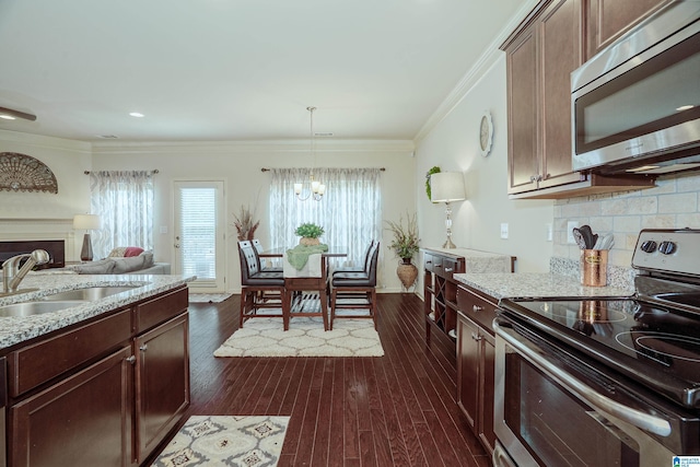4955 Stonecreek Way, Calera, AL 35040 - kitchen with appliances with stainless steel finishes, a chandelier, crown molding, light stone countertops, and dark wood finished floors