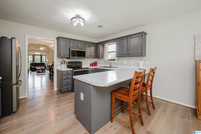 5904 Russet Meadows Way, Helena, AL 35244 - kitchen featuring stainless steel appliances, gray cabinetry, light wood finished floors, a breakfast bar, and a peninsula