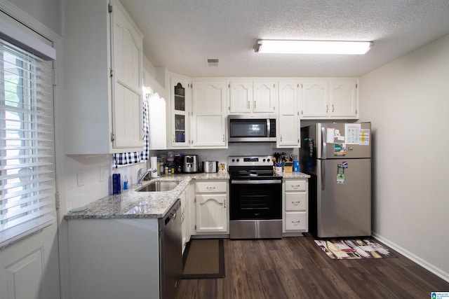 1822 Oakleaf Ln, Center Point, AL 35215 - kitchen featuring stainless steel appliances, white cabinets, dark wood finished floors, light stone countertops, and a textured ceiling