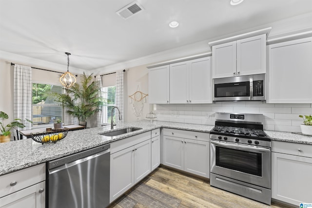 189 Ridgeline Dr, Chelsea, AL 35043 - kitchen with appliances with stainless steel finishes, ornamental molding, decorative backsplash, light wood finished floors, and decorative light fixtures