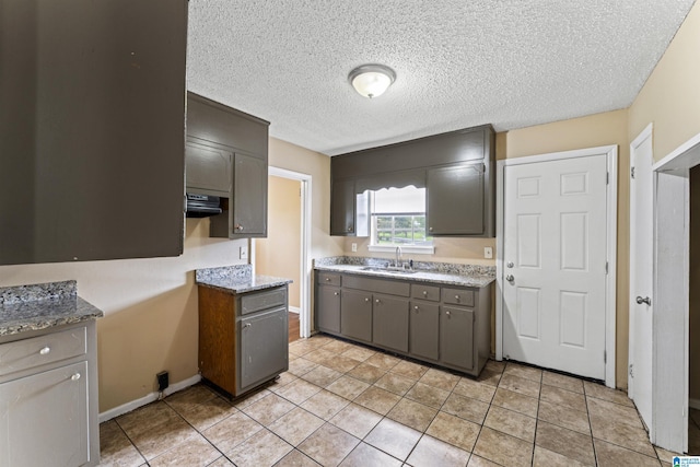 540 Harlem Ave, Hueytown, AL 35023 - kitchen with a textured ceiling, light tile patterned floors, gray cabinets, and exhaust hood