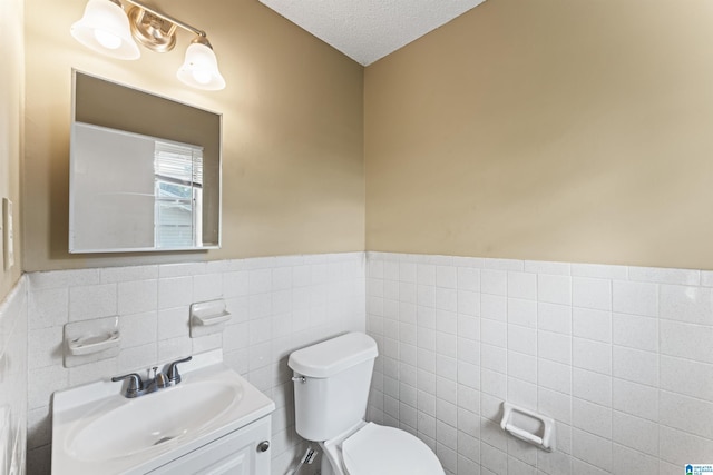 540 Harlem Ave, Hueytown, AL 35023 - half bathroom with tile walls, a wainscoted wall, vanity, and a textured ceiling