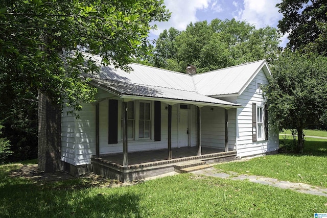 1221 4th Pl, Pleasant Grove, AL 35023 - view of front of property with covered porch, a chimney, a front yard, and a metal roof