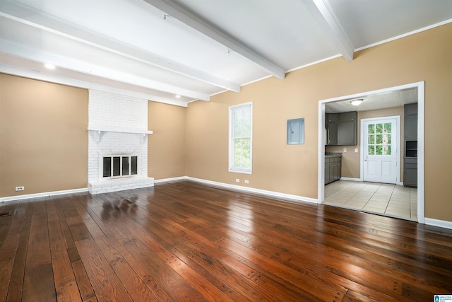 1221 4th Pl, Pleasant Grove, AL 35023 - unfurnished living room with wood-type flooring, beam ceiling, and a brick fireplace