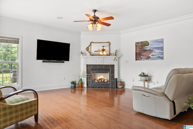 3037 Twelve Stones Rd SE, Owens Cross Roads, AL 35763 - living room featuring a tiled fireplace, a ceiling fan, crown molding, and wood finished floors