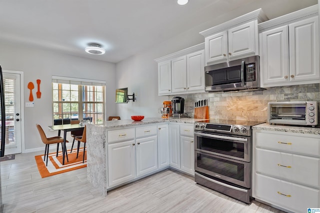 2816 Aster Lake Rd, Helena, AL 35022 - kitchen featuring stainless steel appliances, a peninsula, decorative backsplash, white cabinets, and light stone counters