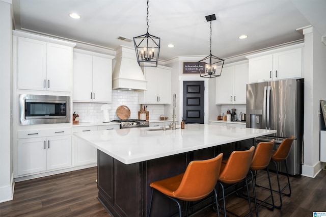 4945 Natalie Way, Trussville, AL 35173 - kitchen with appliances with stainless steel finishes, custom range hood, a kitchen island with sink, light countertops, and dark wood-style flooring
