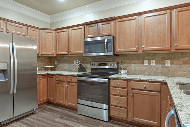 1186 Inverness Cove Way, Hoover, AL 35242 - kitchen featuring stainless steel appliances, crown molding, light wood finished floors, decorative backsplash, and brown cabinetry