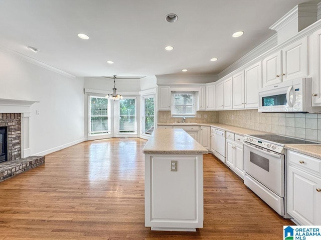 4205 Waterford Ln, Trussville, AL 35173 - kitchen featuring white appliances, a kitchen island, white cabinets, light countertops, and ornamental molding