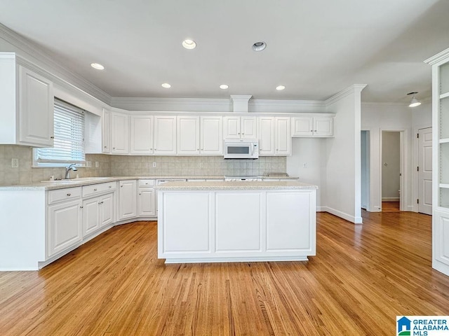 4205 Waterford Ln, Trussville, AL 35173 - kitchen with white microwave, light countertops, light wood-style floors, decorative backsplash, and white cabinets