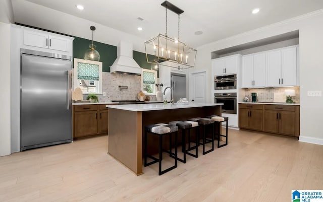 500 Simms Lndg, Pelham, AL 35124 - kitchen with stainless steel appliances, custom range hood, backsplash, light countertops, and light wood-style flooring