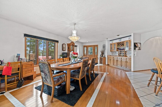 tiled dining room featuring a textured ceiling and a chandelier