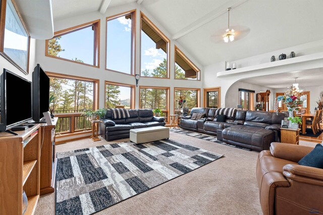 living room with light carpet, high vaulted ceiling, beam ceiling, and ceiling fan with notable chandelier