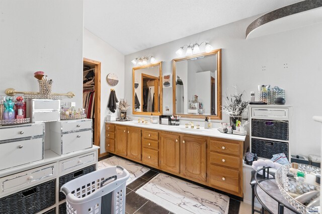 bathroom featuring vaulted ceiling, tile floors, and vanity with extensive cabinet space