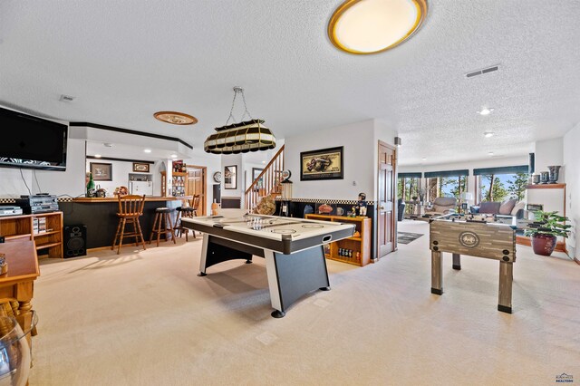 rec room with a textured ceiling and light colored carpet