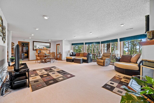 living room featuring a textured ceiling, light colored carpet, and a wealth of natural light