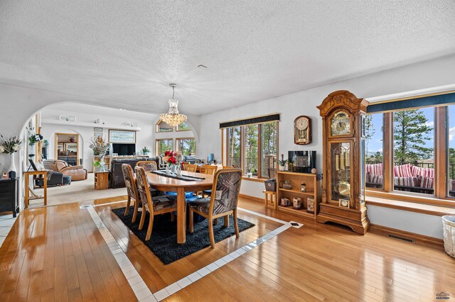 dining space featuring a notable chandelier, a textured ceiling, and light hardwood / wood-style floors