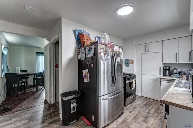601 Haines Ct, Rapid City, SD 57701 - kitchen featuring appliances with stainless steel finishes, tasteful backsplash, white cabinetry, light wood-type flooring, and sink