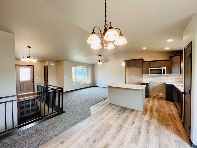 kitchen with hanging light fixtures, tasteful backsplash, a center island, ceiling fan with notable chandelier, and light hardwood / wood-style flooring