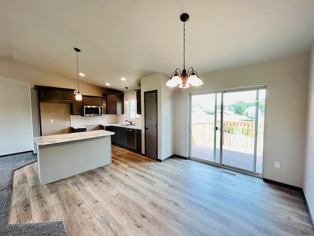 kitchen with pendant lighting, a chandelier, light hardwood / wood-style flooring, vaulted ceiling, and tasteful backsplash