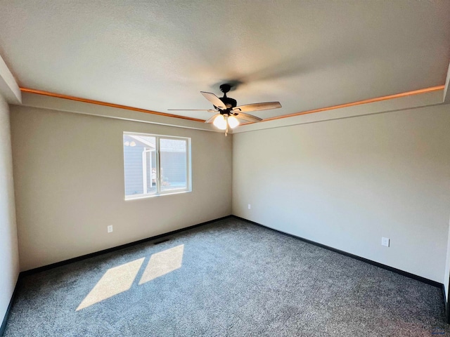 carpeted empty room with ceiling fan and a textured ceiling