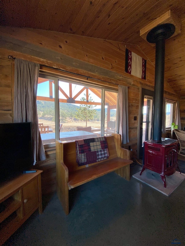 living room featuring wooden walls, a wood stove, plenty of natural light, and wood ceiling