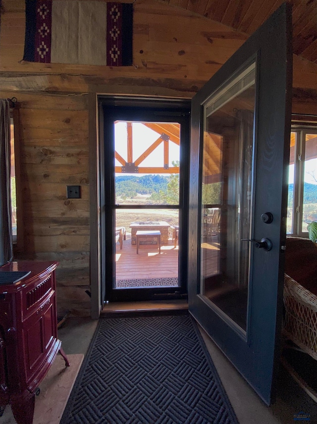 doorway with wooden ceiling, lofted ceiling, and wood walls