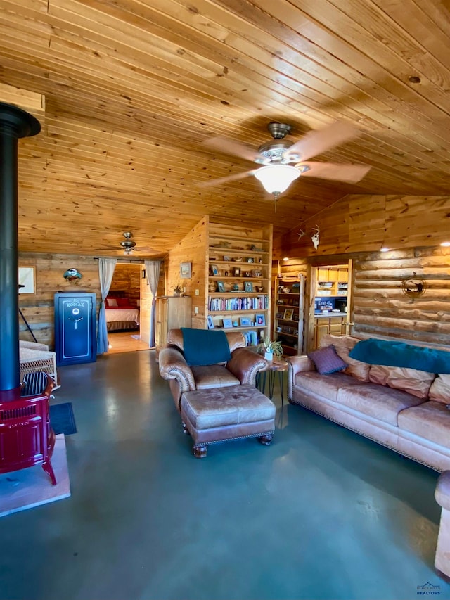 living room with lofted ceiling, ceiling fan, a wood stove, concrete flooring, and wooden ceiling