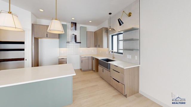 kitchen featuring sink, tasteful backsplash, pendant lighting, and light hardwood / wood-style flooring