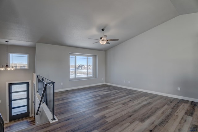 empty room featuring plenty of natural light, dark hardwood / wood-style floors, and vaulted ceiling