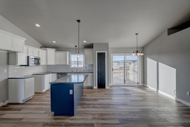 kitchen featuring appliances with stainless steel finishes, light hardwood / wood-style floors, lofted ceiling, white cabinetry, and pendant lighting