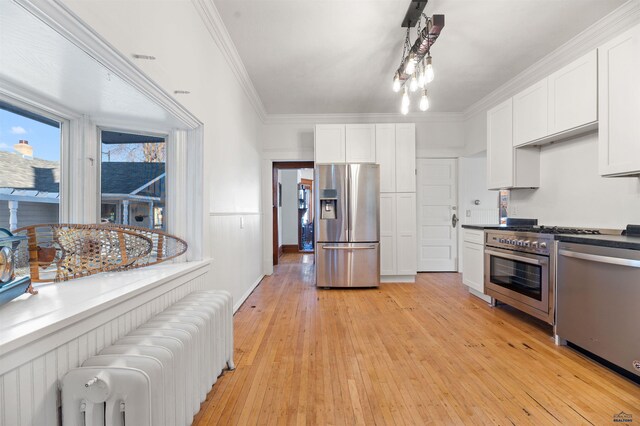 735 8th, Spearfish, SD 57783 - kitchen with radiator heating unit, white cabinetry, crown molding, stainless steel appliances, and light hardwood / wood-style flooring