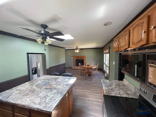 kitchen featuring dark hardwood / wood-style floors, ornamental molding, stainless steel appliances, a kitchen island, and ceiling fan