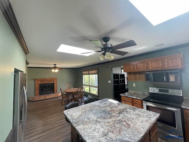 kitchen featuring a kitchen island, stainless steel appliances, ceiling fan, dark hardwood / wood-style floors, and a skylight