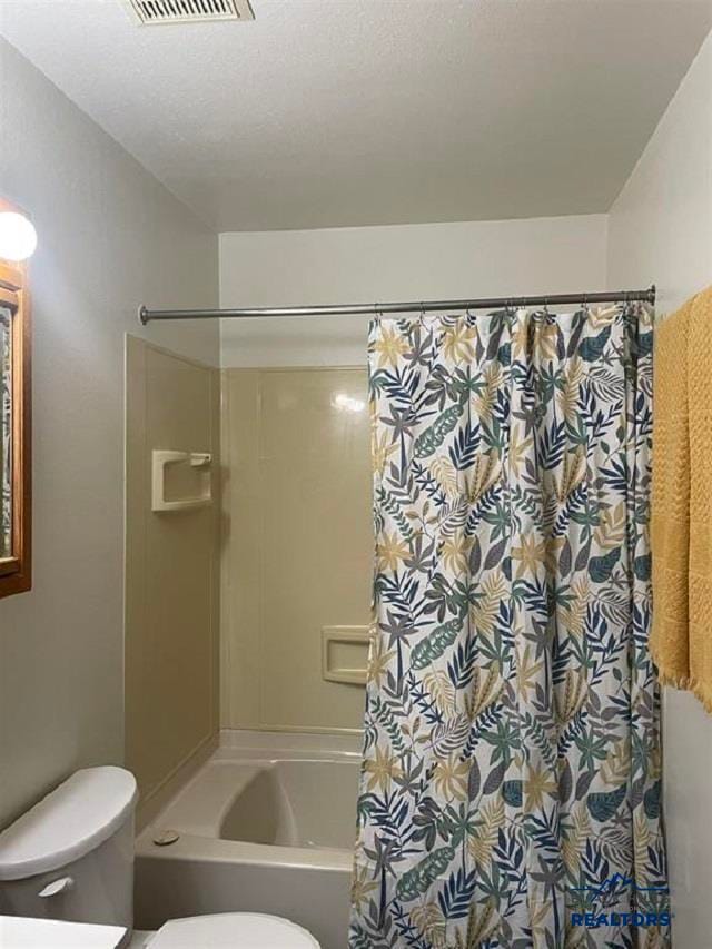 bathroom with shower / bath combo, toilet, and a textured ceiling