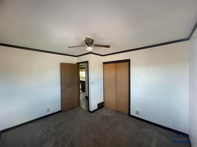 unfurnished bedroom with a closet, dark colored carpet, ceiling fan, and crown molding