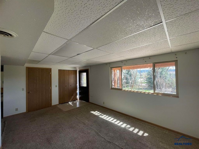 empty room with a drop ceiling and carpet flooring