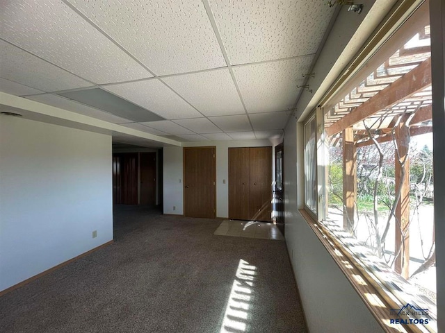 spare room with a paneled ceiling and carpet flooring