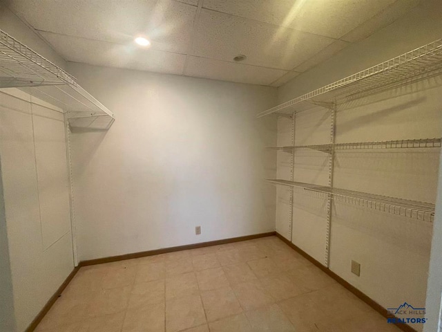 spacious closet featuring a drop ceiling and light tile floors