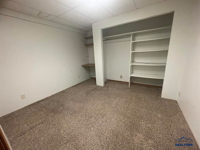 unfurnished bedroom with a drop ceiling and carpet flooring