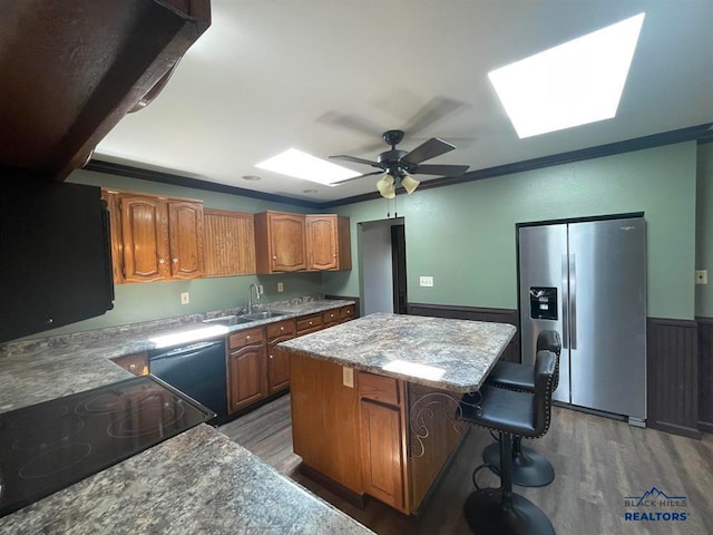 kitchen with stainless steel refrigerator with ice dispenser, a skylight, sink, dark hardwood / wood-style flooring, and a center island