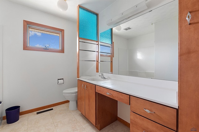 bathroom with tile flooring, vanity, toilet, and a healthy amount of sunlight