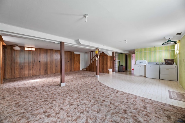 basement featuring independent washer and dryer, light carpet, and wooden walls