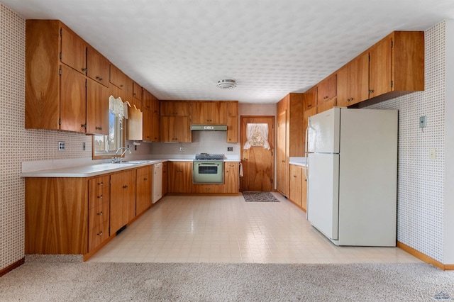 kitchen with sink, white refrigerator, light tile floors, and stove