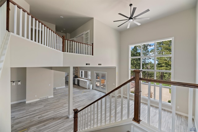 staircase with ceiling fan and light hardwood / wood-style floors